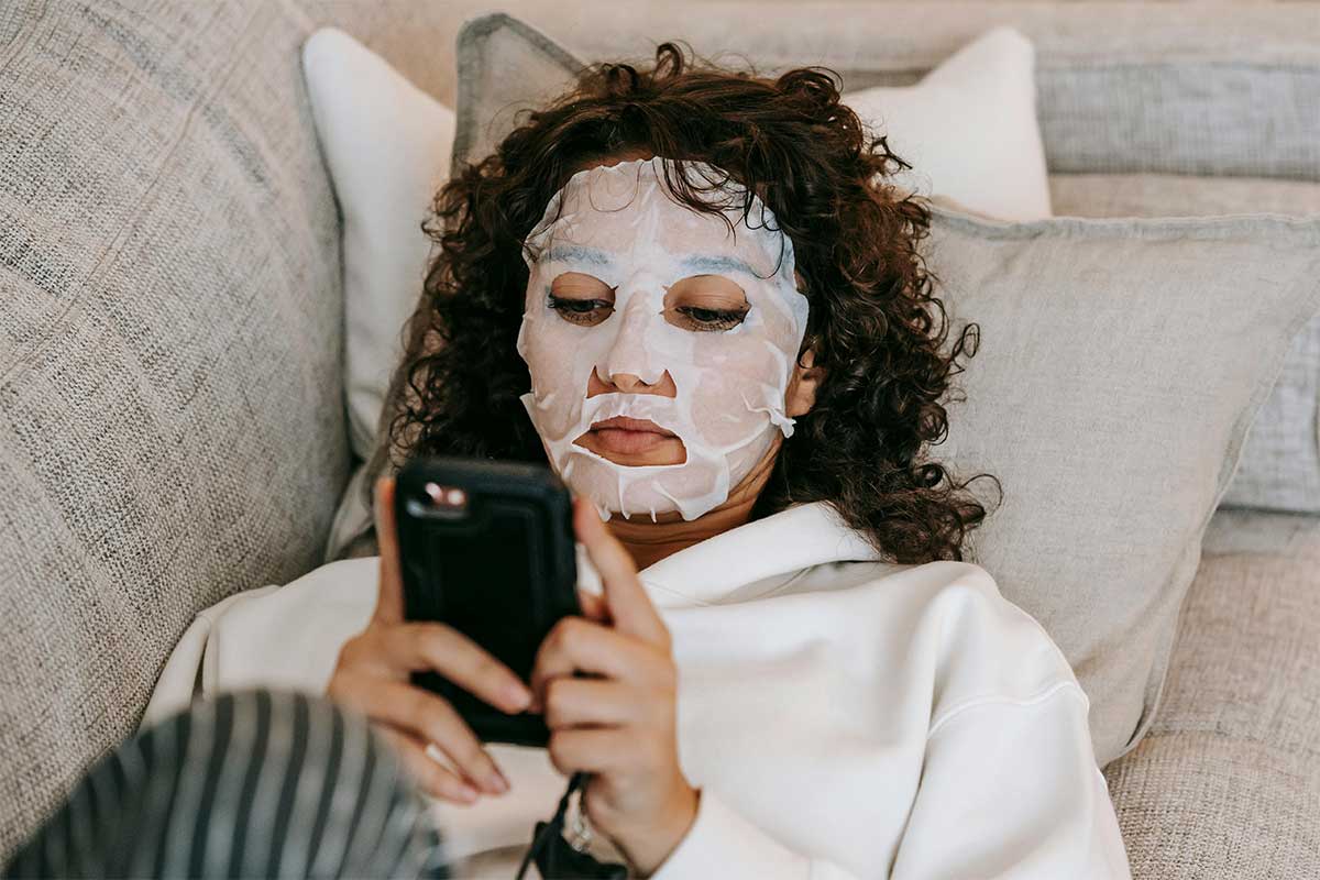 Cheap self-care ideas at home — a young woman relaxing with an affordable sheet mask