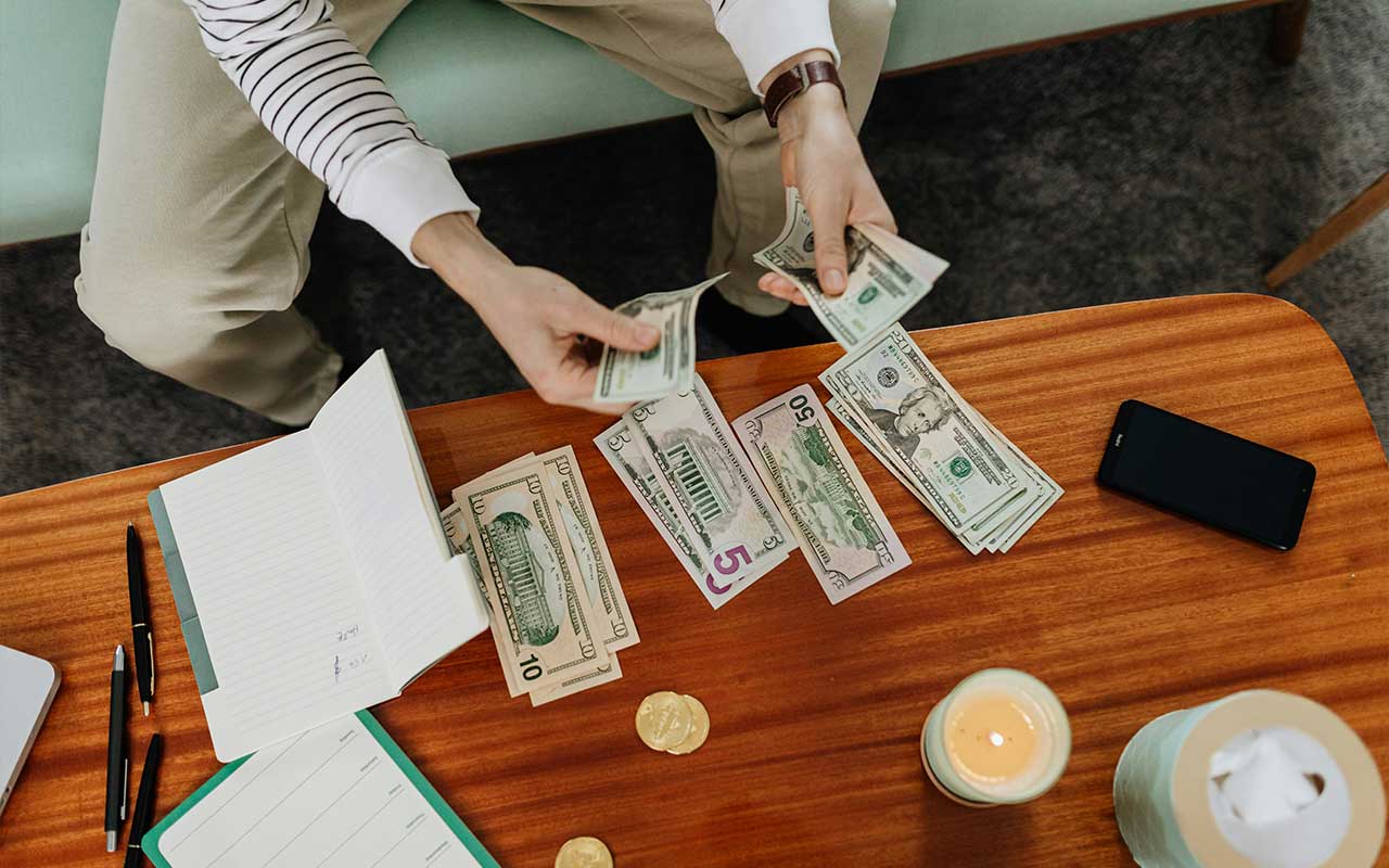 Counting cash saved during a 30 day no spend challenge with a planner and pen — tracking every dollar not spent