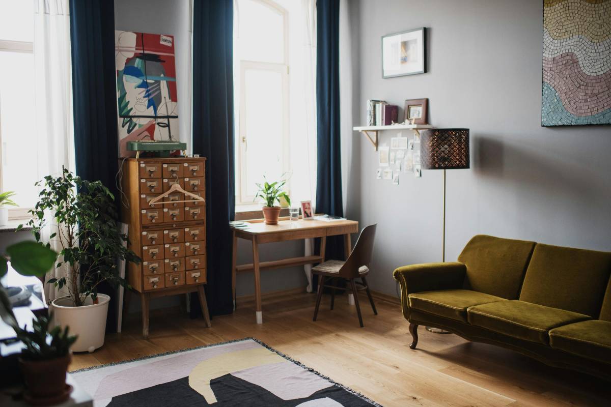 A cozy rental living area with a large neutral rug, a slipcovered couch, warm lamp light and plants — apartment decorating on a budget