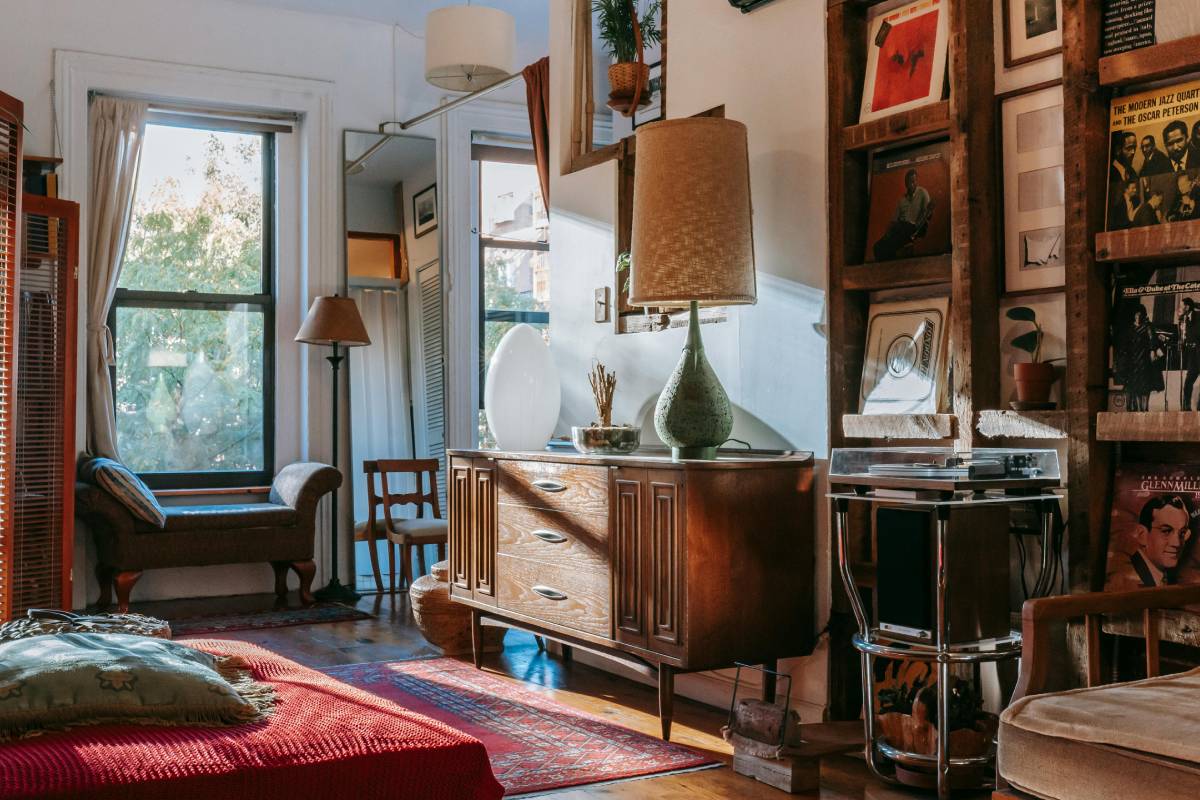 A thrifted wood dresser styled with a lamp, a framed photo and a plant in a budget rental apartment — cheap apartment decor