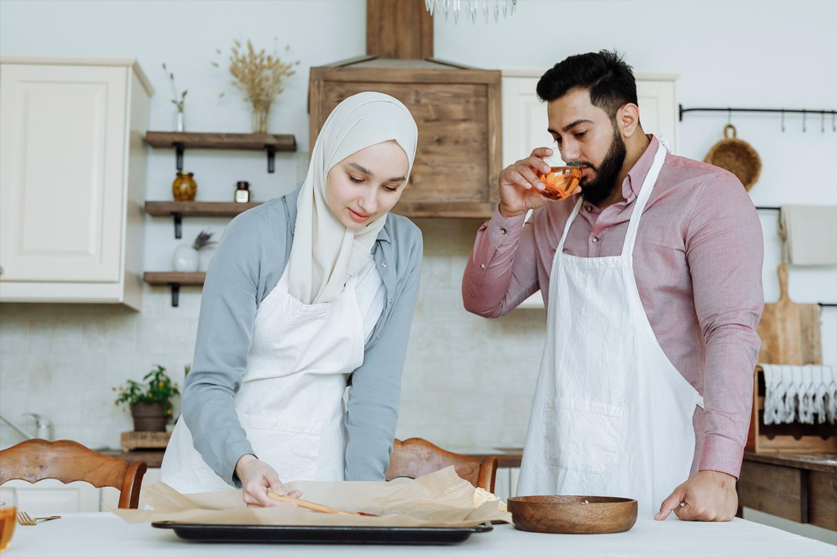 A couple cooking dinner together at home as a cheap date idea, with fresh ingredients on the counter