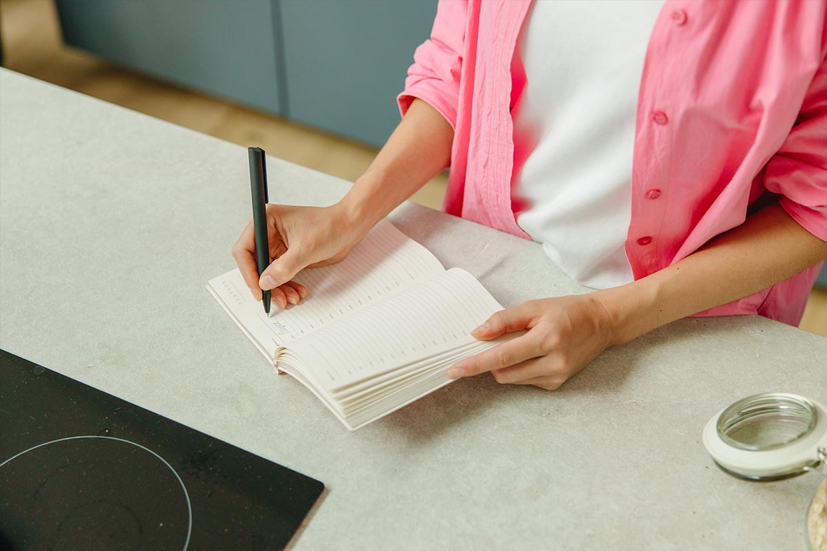 A weekly grocery list and meal plan written in a notebook — meal planning on a tight budget