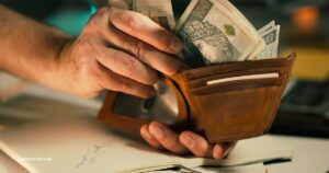 Budgeting for beginners — hands counting cash next to documents and a pen on a desk