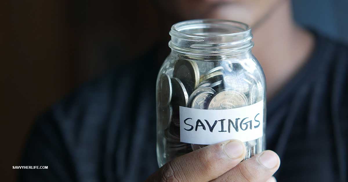 How to build an emergency fund — cash and coins saved in a labeled jar next to a notebook and a phone showing a savings balance