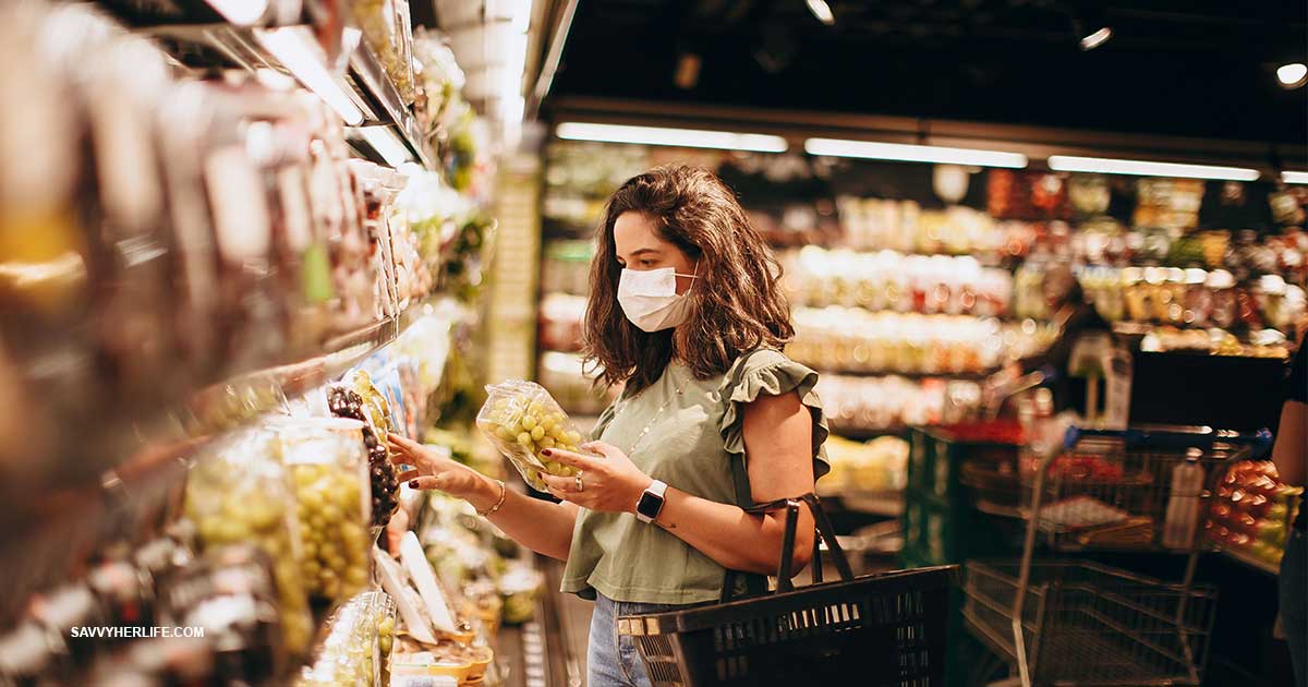 How to save money on groceries — a woman choosing fresh produce with a basket at the grocery store